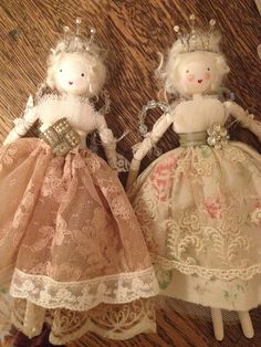 two dolls are sitting on the floor next to each other, wearing dresses and tiaras