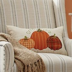 a chair with two pumpkins on it and a throw pillow in the back seat