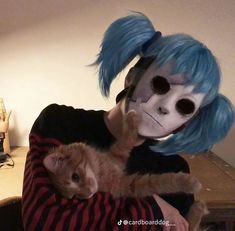 a person holding a cat in their arms with a skeleton mask on top of them