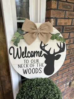 a welcome sign hanging on the front door of a house with a deer's head