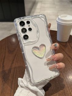 a woman's hand holding an iphone case with a heart design on the back