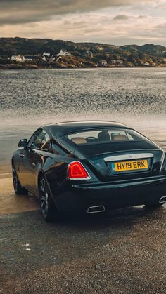 a black sports car parked next to the water