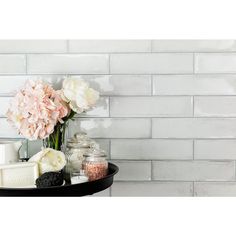 flowers and soaps are sitting on a tray in front of a white brick wall