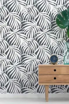 a plant is sitting on top of a dresser in front of a patterned wallpaper