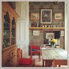 a dining room table and chairs in front of a wall with pictures on the walls