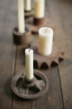 several candles sitting on top of a wooden table next to an iron sprinkle