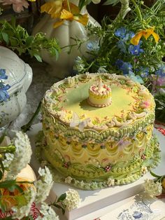 a yellow cake sitting on top of a table next to flowers