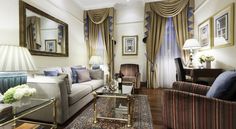 a living room with two couches, chairs and a coffee table in front of a mirror