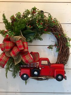 a christmas wreath with a red truck and greenery