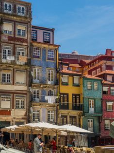 people sitting at tables in front of colorful buildings