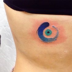 a woman's stomach with a blue and green circle tattoo on the side of her belly