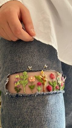 someone is holding their jeans with flowers on them