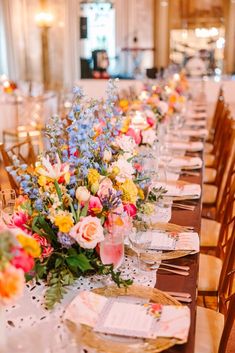 a long table is set with flowers and place settings for dinner guests to sit at