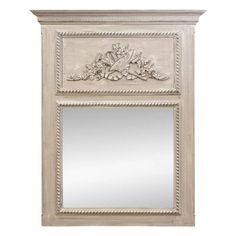 a white mirror with an ornate design on the top and bottom panel, in front of a