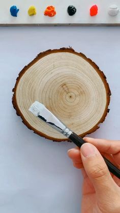 a person holding a paintbrush in front of a piece of wood that has been cut into