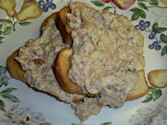 two pieces of bread topped with meat and cheese on top of it, sitting on a plate