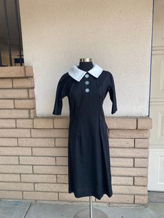 Lovely vintage 1940's uniform dress in solid jet black.  Double pointed peter pan collar with white on top and black underneath.  Large white round buttons on the chest and a single snap closure above the top button.  Gusset underarms.  Inverted shoulder pleats and an adorable hip bow in the back.  The only opening is the 3 buttons.  Shoulder area is somewhat narrow.  Rare find in excellent vintage condition with no issues.  There is a clustered thread spot on the back that looks to be a flaw in fabric manufacturing.  (see next to last pic) The only tag is the order no. tag.  The fabric has a thin horizontal slub, possibly a silk shantung.   Size small is just an estimate.  Please check measurements for an accurate fit.   Dress was measured across the front side lying flat. underarm to und Servant Dress, White Uniform, Bombshell Dress, Wrap Sweater Dress, Maid Uniform, Uniform Dress, Shirtwaist Dress, House Dress, Dress Midi