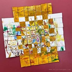 a piece of art that is on top of a red surface with yellow and green squares