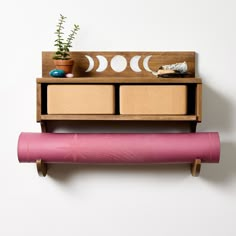 a wooden shelf with two drawers and a pink yoga mat next to it on top of a white wall