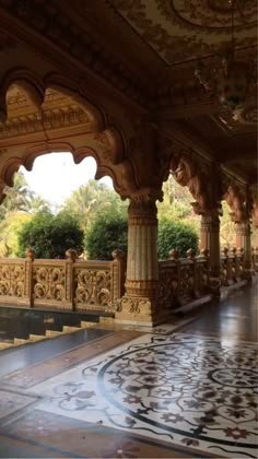 the inside of an ornate building with marble flooring and pillars, surrounded by greenery