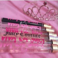 four lip glosses are lined up next to a tiara on a pink background