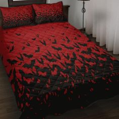 a bed covered in red and black bats on it's cover with matching pillows