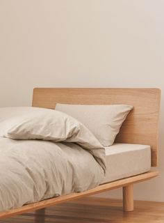 a bed with two pillows on top of it and a wooden frame in the middle