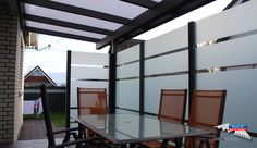 an outdoor dining area with glass table and chairs