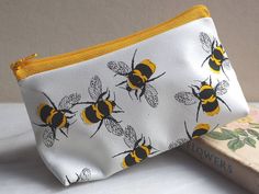 A soft leather white and yellow makeup bag that can also be used as a pencil case or toiletries bag. This charming leather makeup bag has our distinctive bee print in sunny yellow and black printed on white leather. The yellow zip finishes off this lovely leather pouch. The pattern has a really fresh feel and looks great on a dressing table or bathroom shelf.   This would make a great gift for a Mum or Mother-in-law and is perfect for Christmas.  We can gift wrap in a black envelope with gold em Honey Bee Makeup, Bee Makeup, Leather Zip Pouch, Cute Makeup Bags, Leather Makeup Bag, Black Envelopes, Yellow Bee, Bumble Bees, Simple Leather