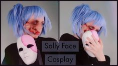 a woman with blue hair and makeup holding a cell phone to her face while wearing a creepy mask