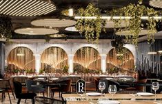 the interior of a restaurant with tables, chairs and plants hanging from the ceiling above