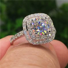 a close up of a person's hand holding an engagement ring with diamonds on it