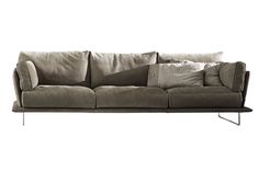 a gray couch with pillows on it sitting in front of a white wall