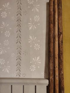 the wall paper is white and has flowers on it, along with two wooden poles