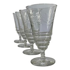 four clear wine glasses are lined up on a white background, with one empty glass in the middle