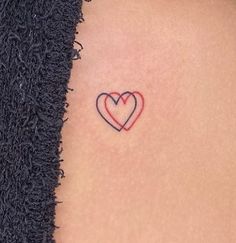 a small heart tattoo on the back of a woman's left upper arm,