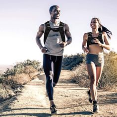 a man and woman running down a dirt road