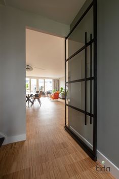 an empty living room with wood floors and sliding glass doors that lead into the dining area