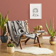 a chair with a blanket on it next to some plants and a potted plant