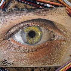 an eye is surrounded by colored pencils and crayons