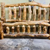 a wooden bench made out of logs sitting on top of a stone floor next to a wall