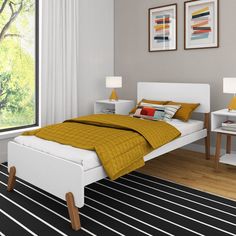 a white bed sitting in a bedroom next to a window with yellow blankets on it