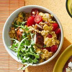 there is a bowl of food on the table next to a plate with bread and salad