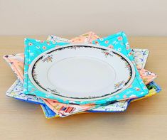 a stack of colorful plates sitting on top of a wooden table