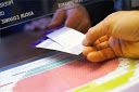 a person holding a piece of paper on top of a table next to a keyboard