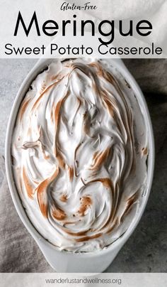 a white bowl filled with whipped cream on top of a gray table cloth next to a spoon