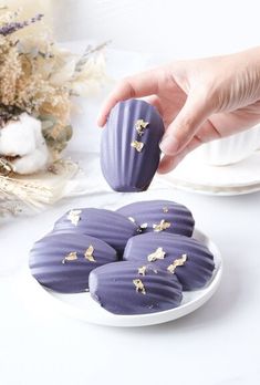 a person is picking up some kind of purple dessert from a plate on the table