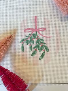 two small christmas trees on a table with pink and green decorations in front of them