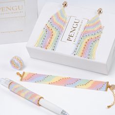 a pair of colorful bracelets next to a white box with gold chains on it