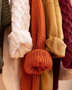 many different colored scarves are hanging on a rack with one knot in the middle